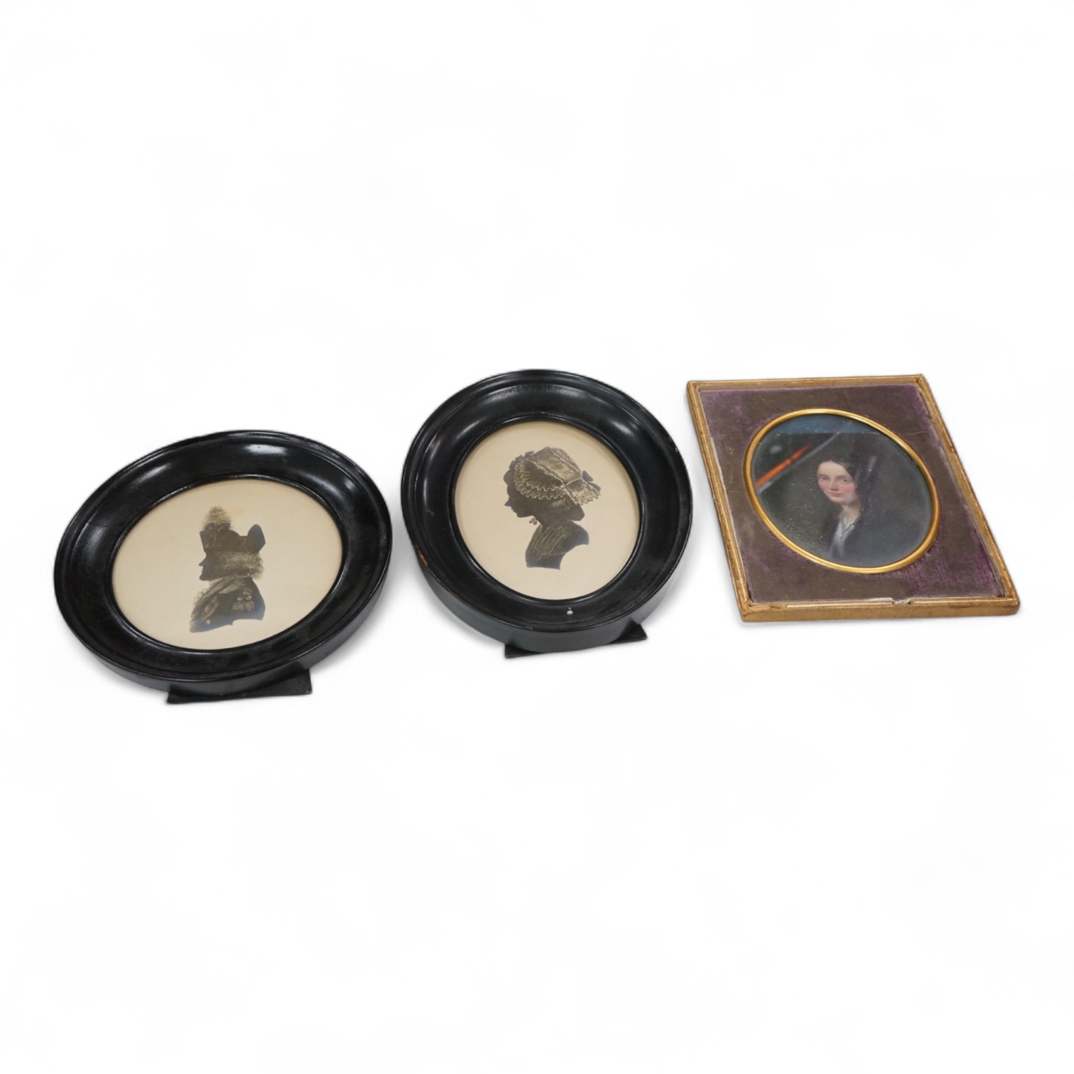 19th century School, two oval framed printed silhouettes and an original oil, Portrait miniature of a mid Victorian lady with ringlets, largest 12 x 9cm